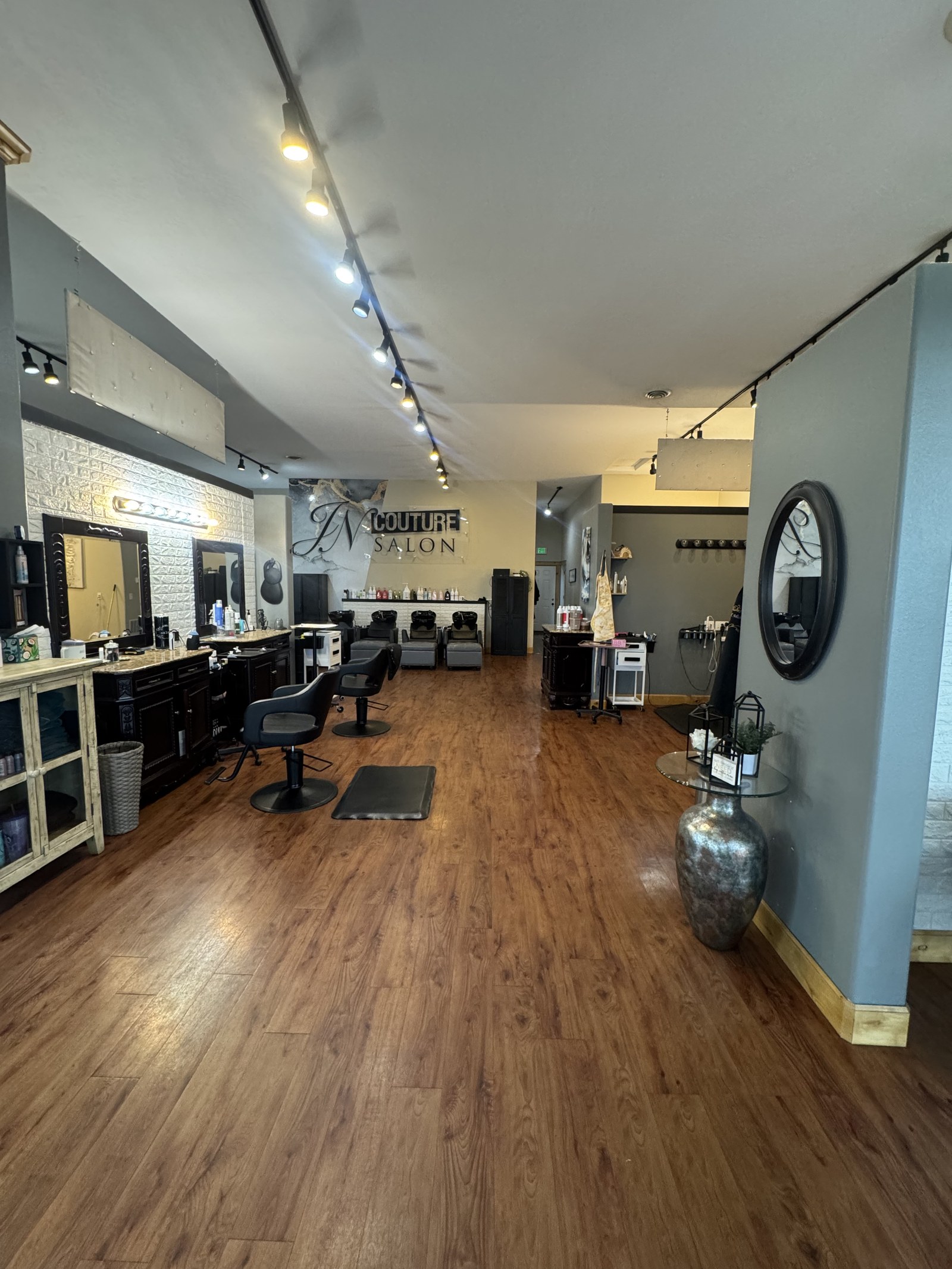 JN Couture Salon main styling floor in Hayden, Idaho — branded back wall, styling stations, hardwood floors